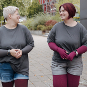 Auf dem Bild sieht man zwei Frauen, die Kompressionsstrümpfe tragen und sich im Gespräch miteinander anlächeln.