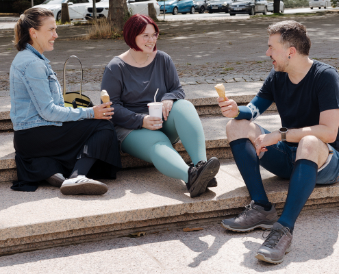 Auf dem Bild sieht man zwei Frauen und einen Mann, die sich unterhalten, zusammen lachen und ein Eis essen. Alle tragen Kompressionsstrümpfe in verschiedenen Ausführungen.